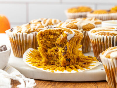 A freshly baked pumpkin chocolate chip muffin with a bite taken out of it.