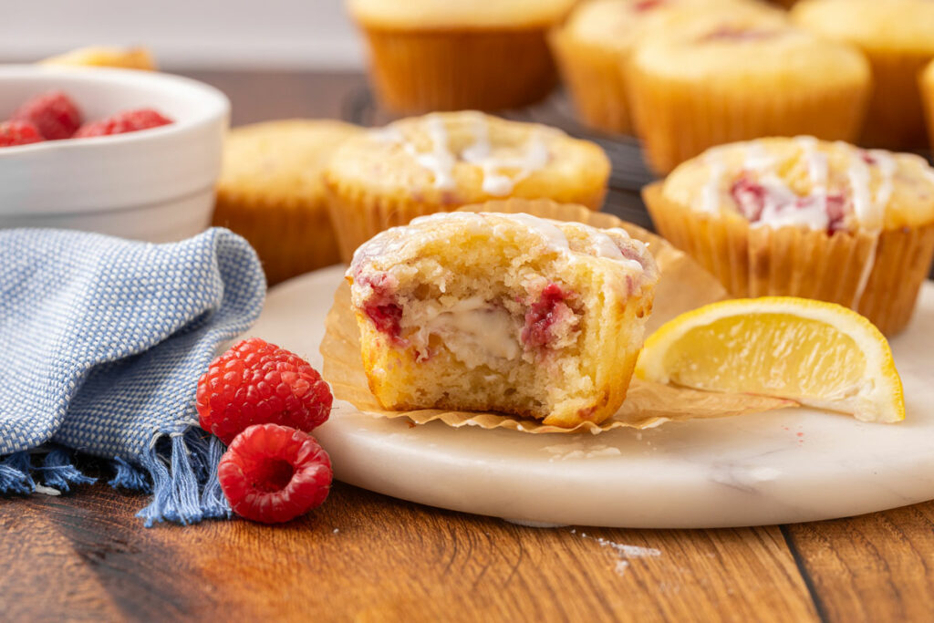 A baked raspberry cream cheese muffin with a bite missing to show the cream cheese filling.