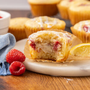 A baked raspberry cream cheese muffin with a bite missing to show the cream cheese filling.