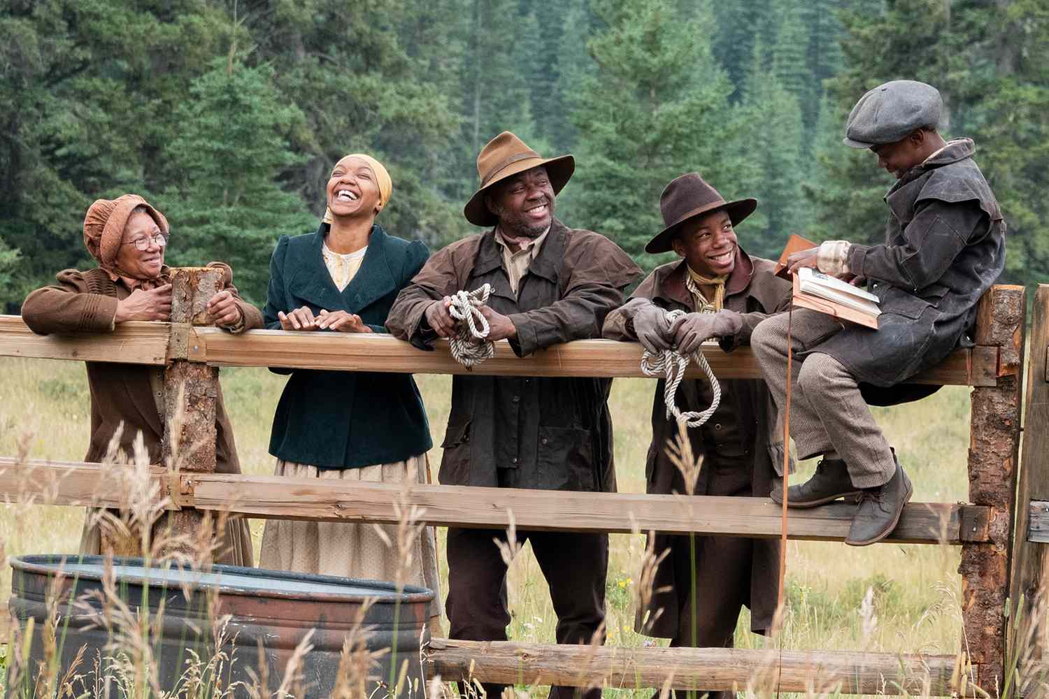 A family sitting on a wooden fence.