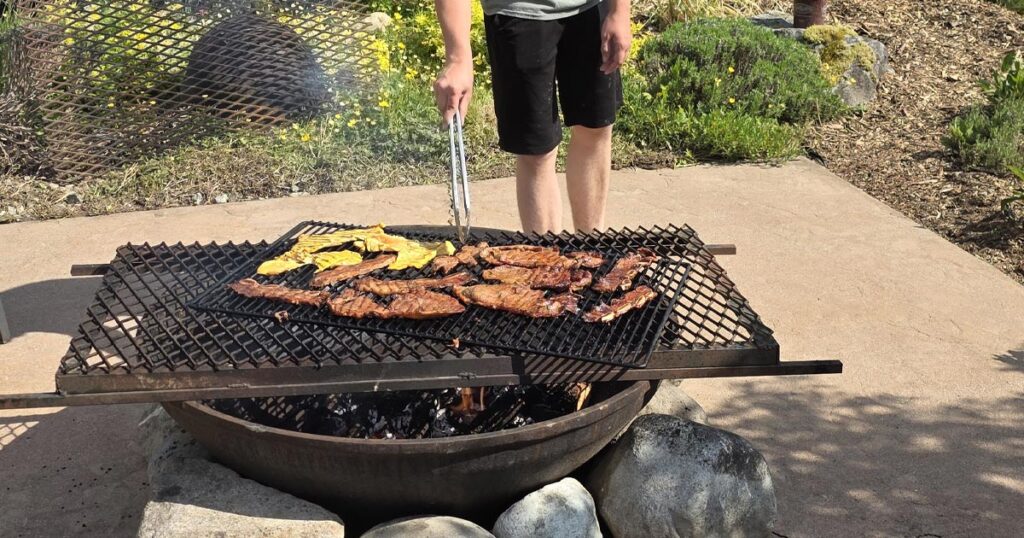 A young man cooking food on a fire pit.