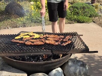 A young man cooking food on a fire pit.