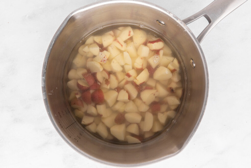 Boiling chopped red potatoes in a saucepan.