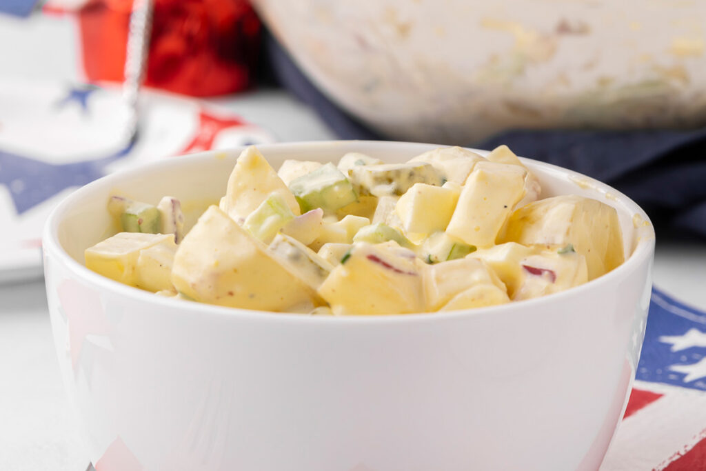 A white bowl filled with creamy potato salad.
