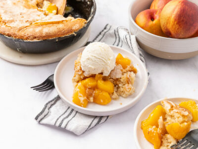 Peach cobbler served on a plate with vanilla ice cream on top.