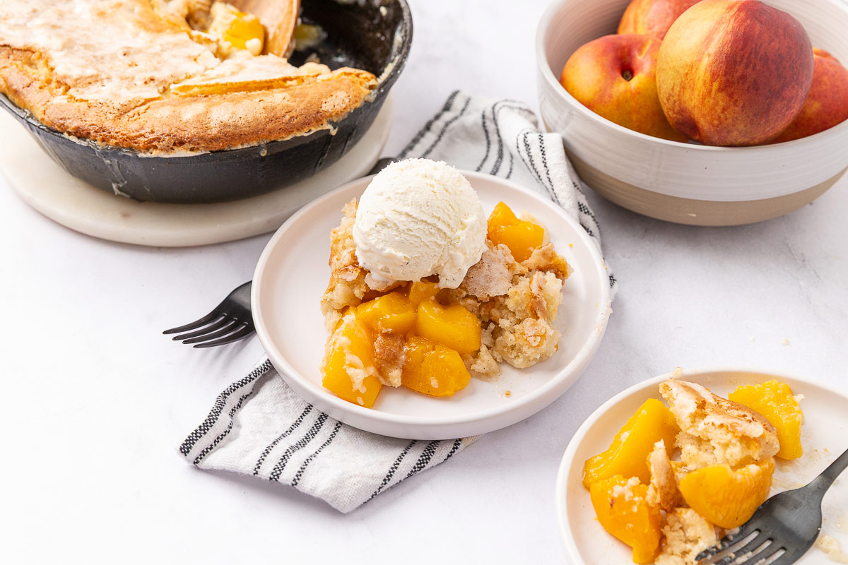 Peach cobbler served on a plate with vanilla ice cream on top.