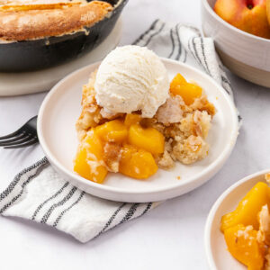 Peach cobbler served on a white plate.