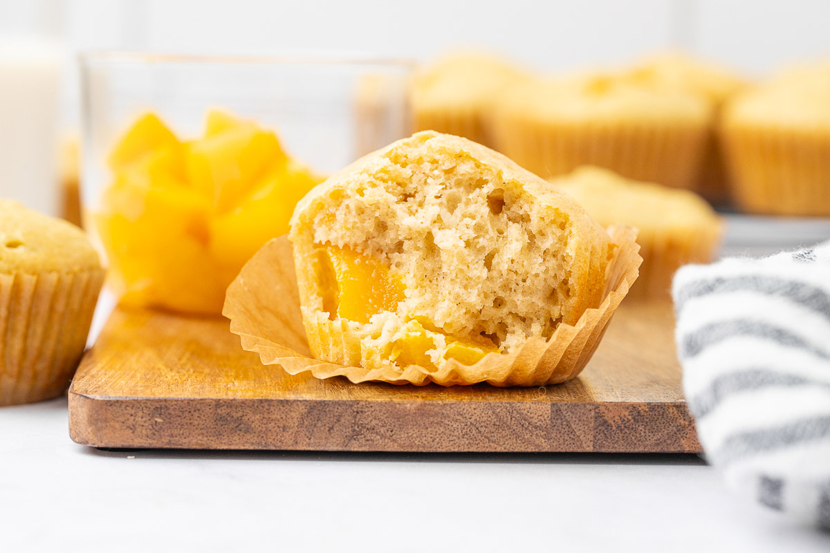 A freshly baked peach muffin with a bite missing.