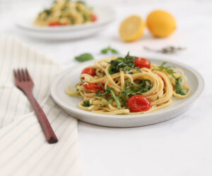 Roasted tomato linguine on a white table with fork and napkin