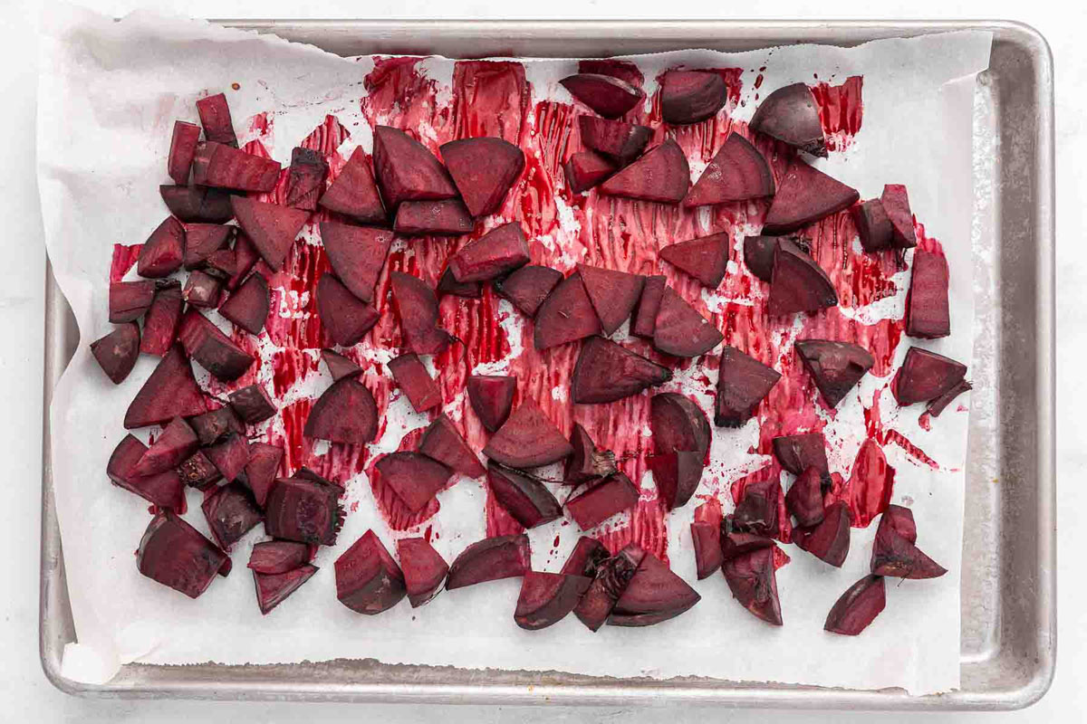 Boiled and chopped beets arranged on a sheet pan ready to roast in the oven.