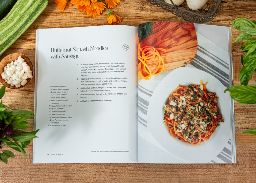 Photo of Plated By Season Magazine on a butcher block counter top with fresh produce around it