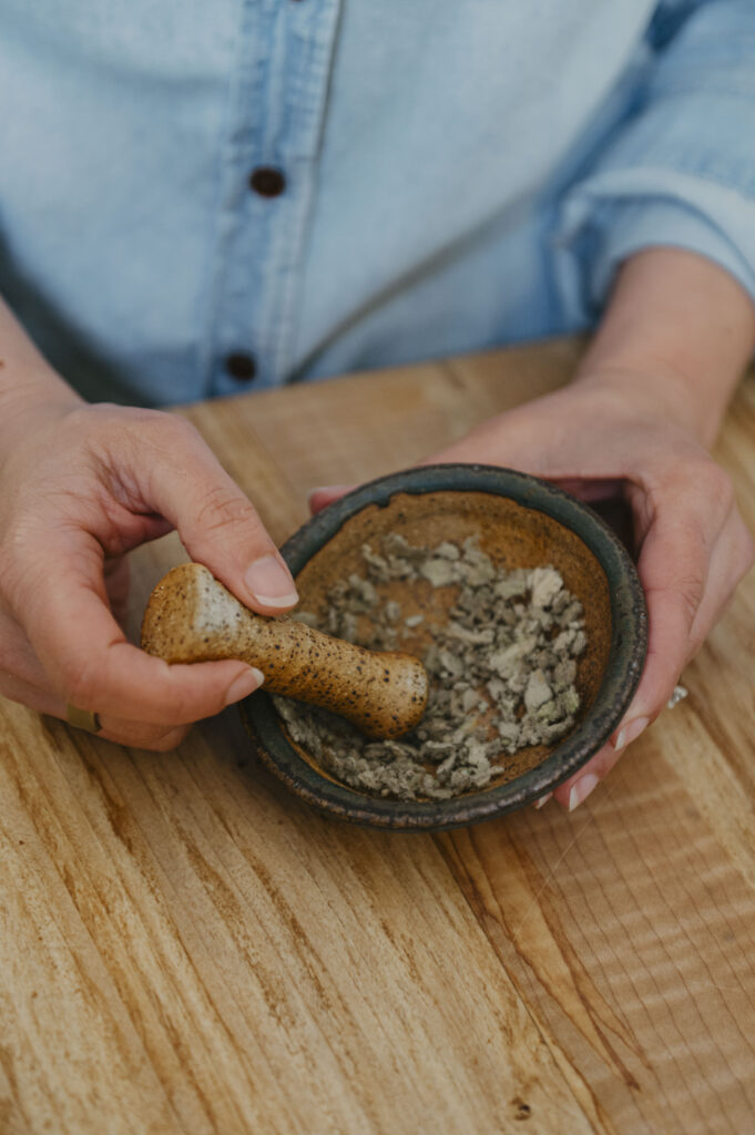 Woman with herbs in a pottery mortar and pestal