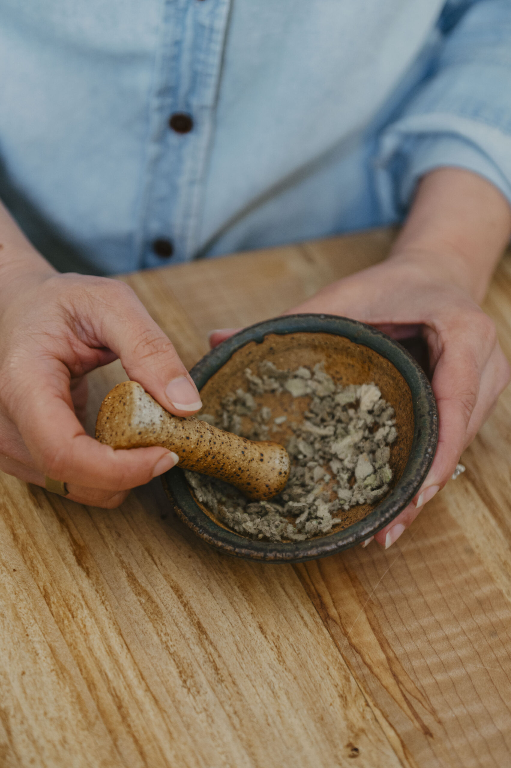 Woman with herbs in a pottery mortar and pestal
