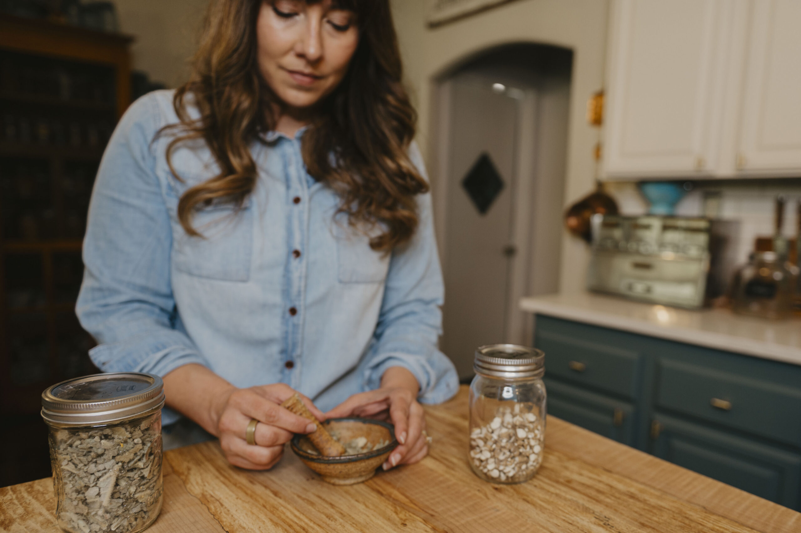 A woman mixing herbs in the kitchen.