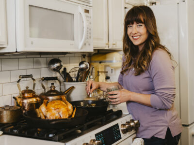 A woman seasoning a whole roasted chicken.
