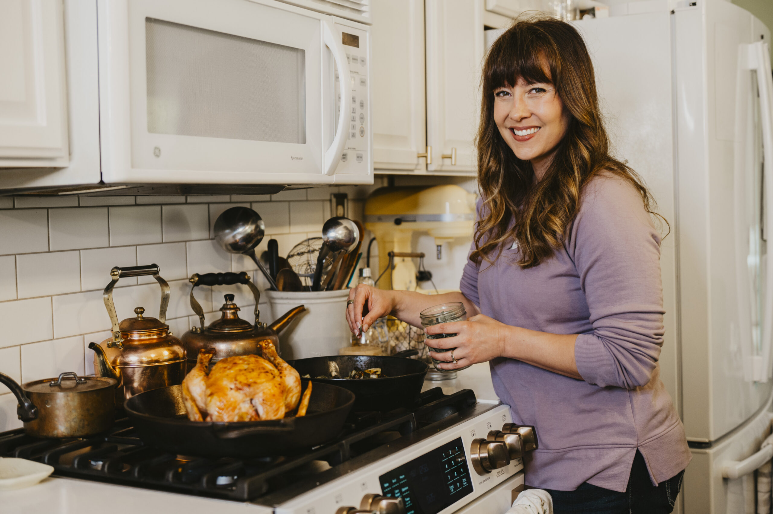 A woman seasoning a whole roasted chicken.