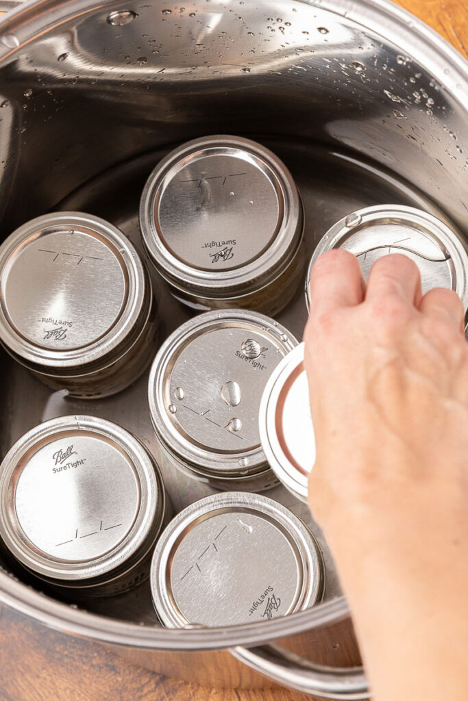 Placing jars into a water bath canner.