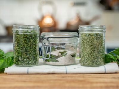 Basil salt three ways in jars on a counter.