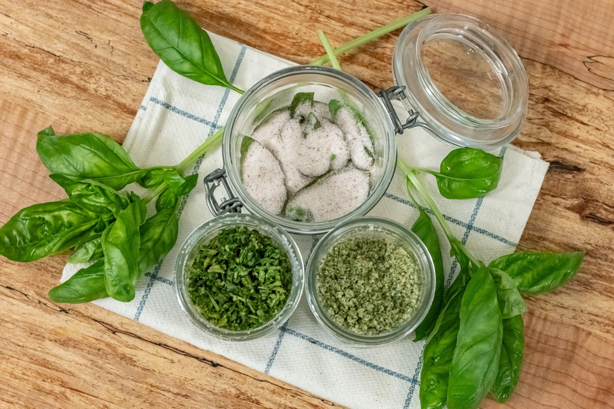 Basil salt three ways in jars on a counter.