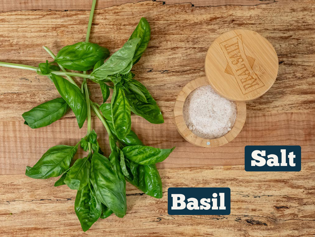 Fresh basil and salt on a wooden counter.
