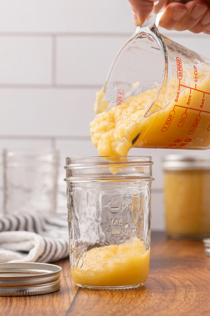 Applesauce being poured into a canning jar.