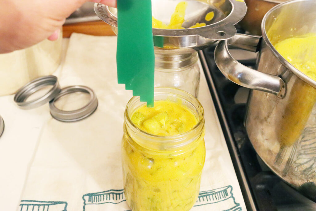 A headspace measurer measuring the headspace of a jar of mustard pickles.