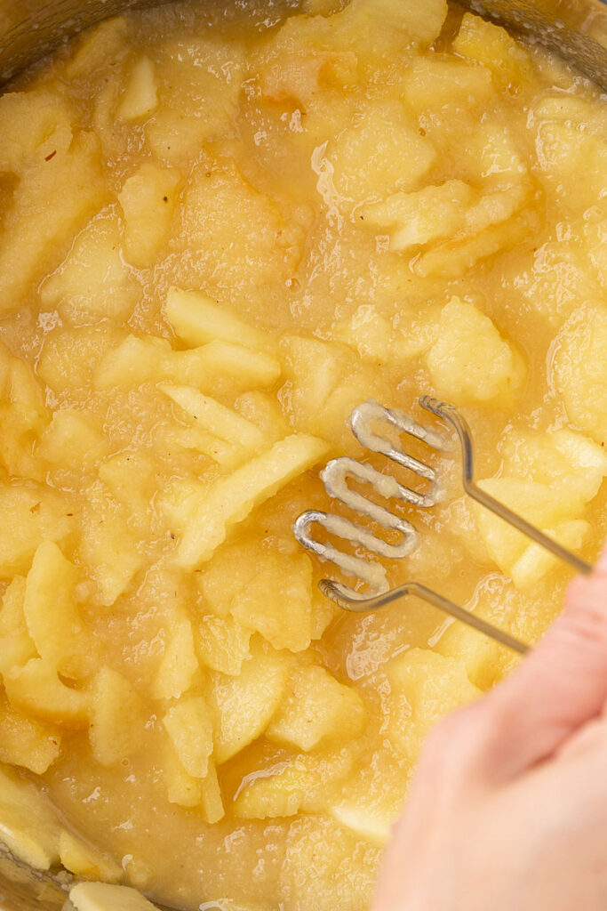 Cooked apples being mashed into applesauce.