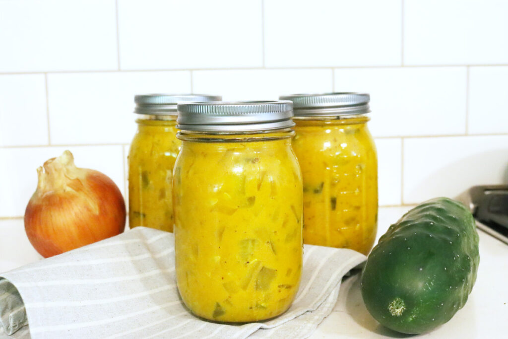 Jars of mustard pickles sitting on a towel-lined counter.