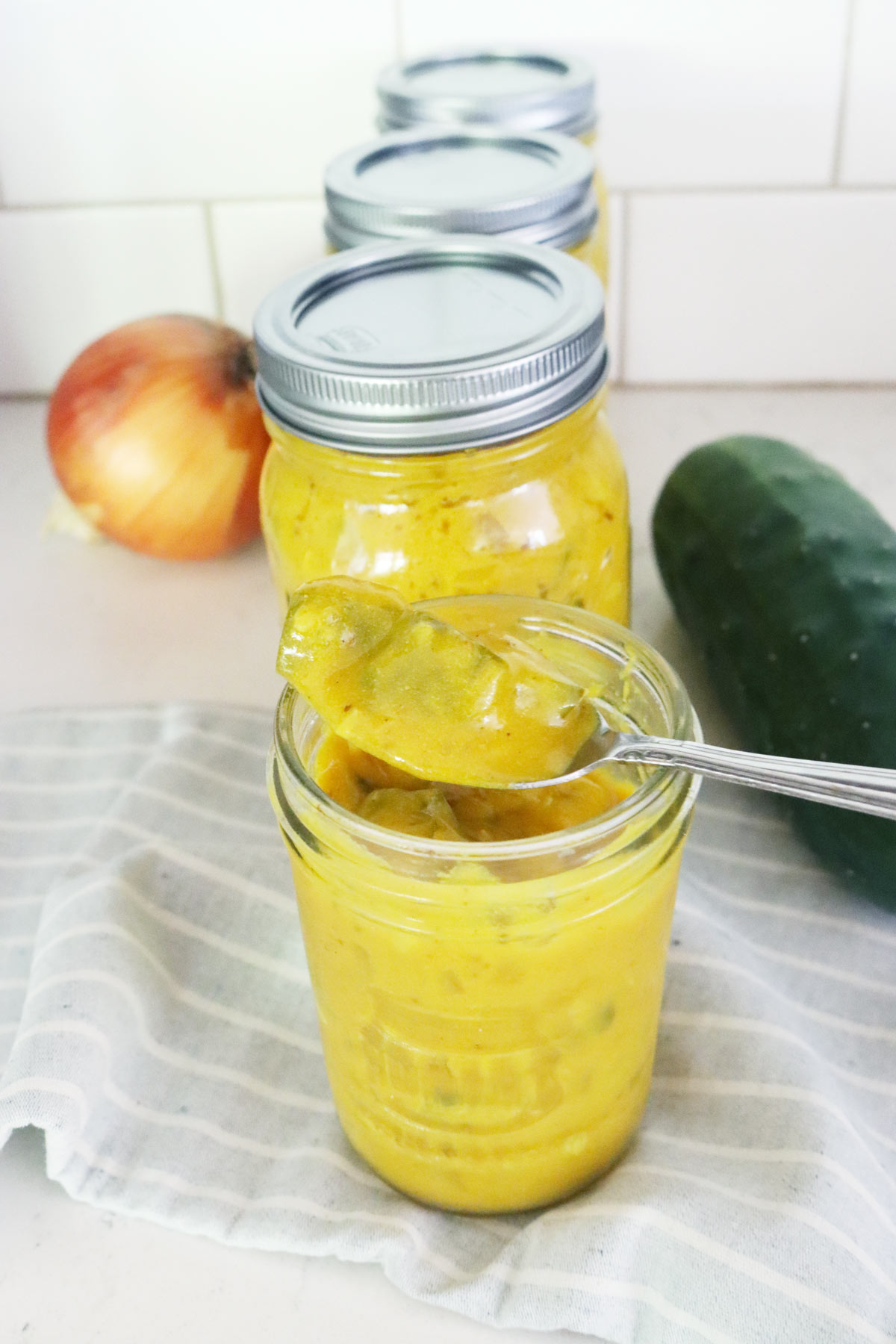 A spoon taking a scoop of homemade mustard pickles.