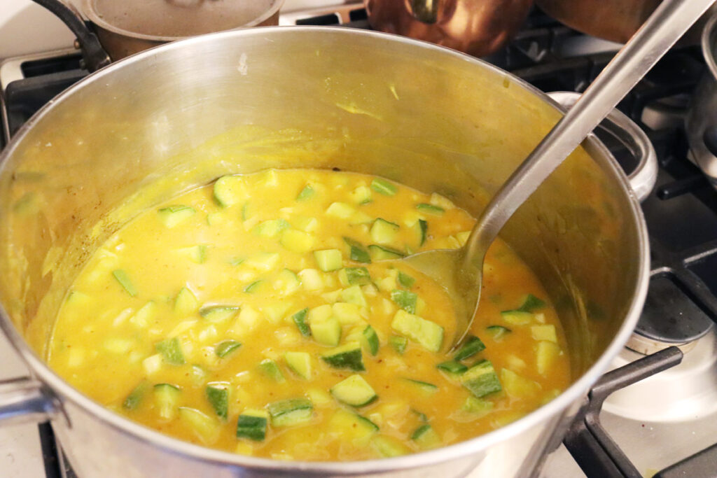 Mustard pickles being stirred in a pot.