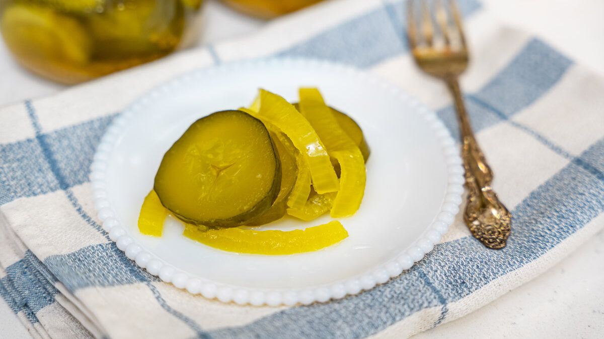 Bread and butter pickles on a white plate.