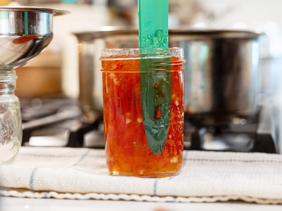 A bubble remover in a jar of red pepper jelly.
