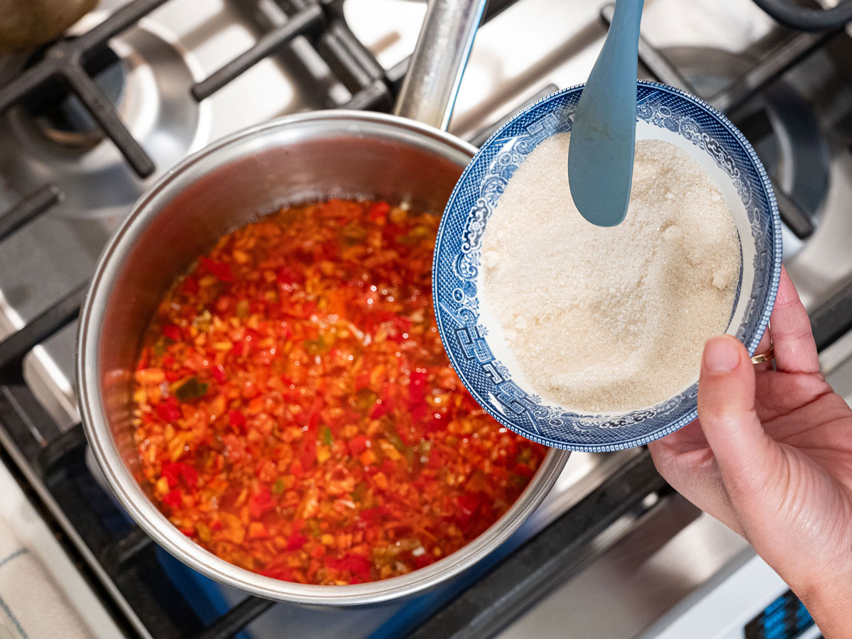 Sugar being added to a pot of red pepper jelly.