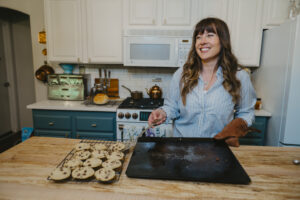 Woman laughing taking chocolate chip cookies off cookie sheet onto cooling rack