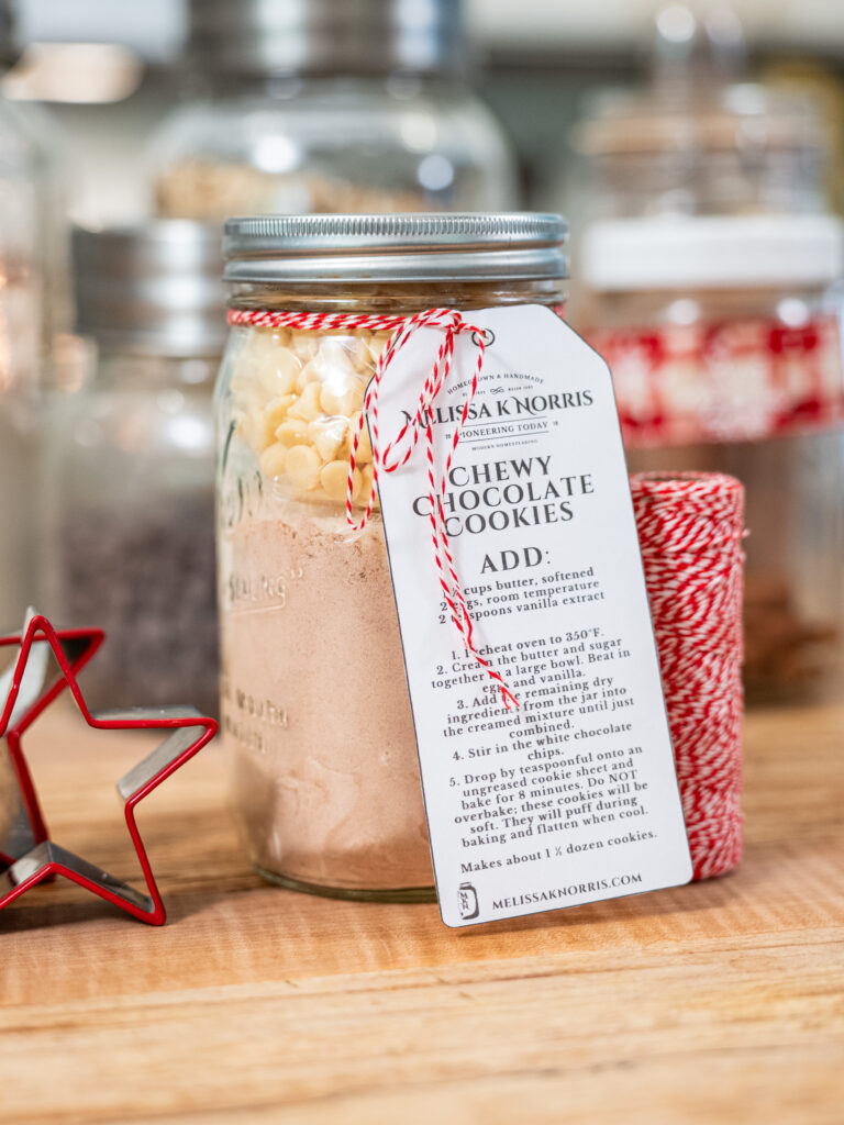 Jar of homemade cookie mix with a gifting label tied to it with red and white twine