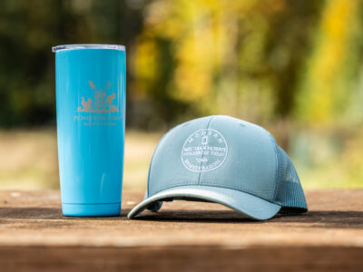 Trucker hat and stainless steel Pioneering Today Tumbler on a table