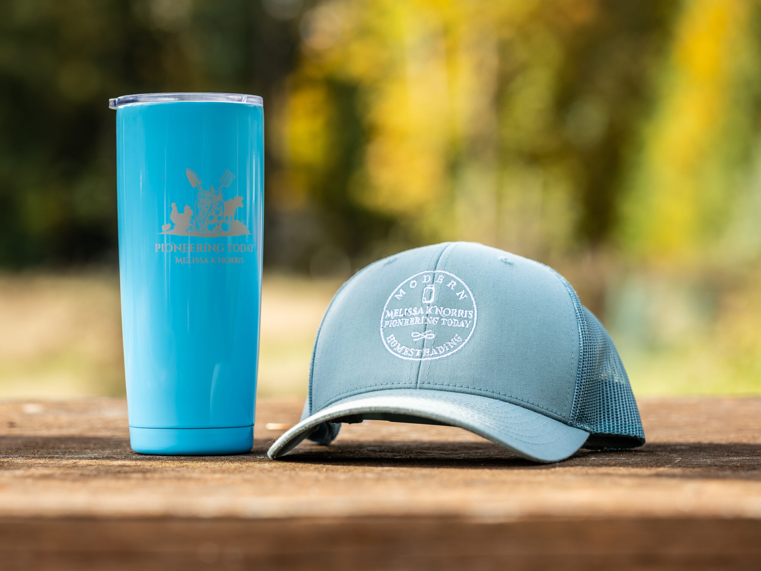 Trucker hat and stainless steel Pioneering Today Tumbler on a table