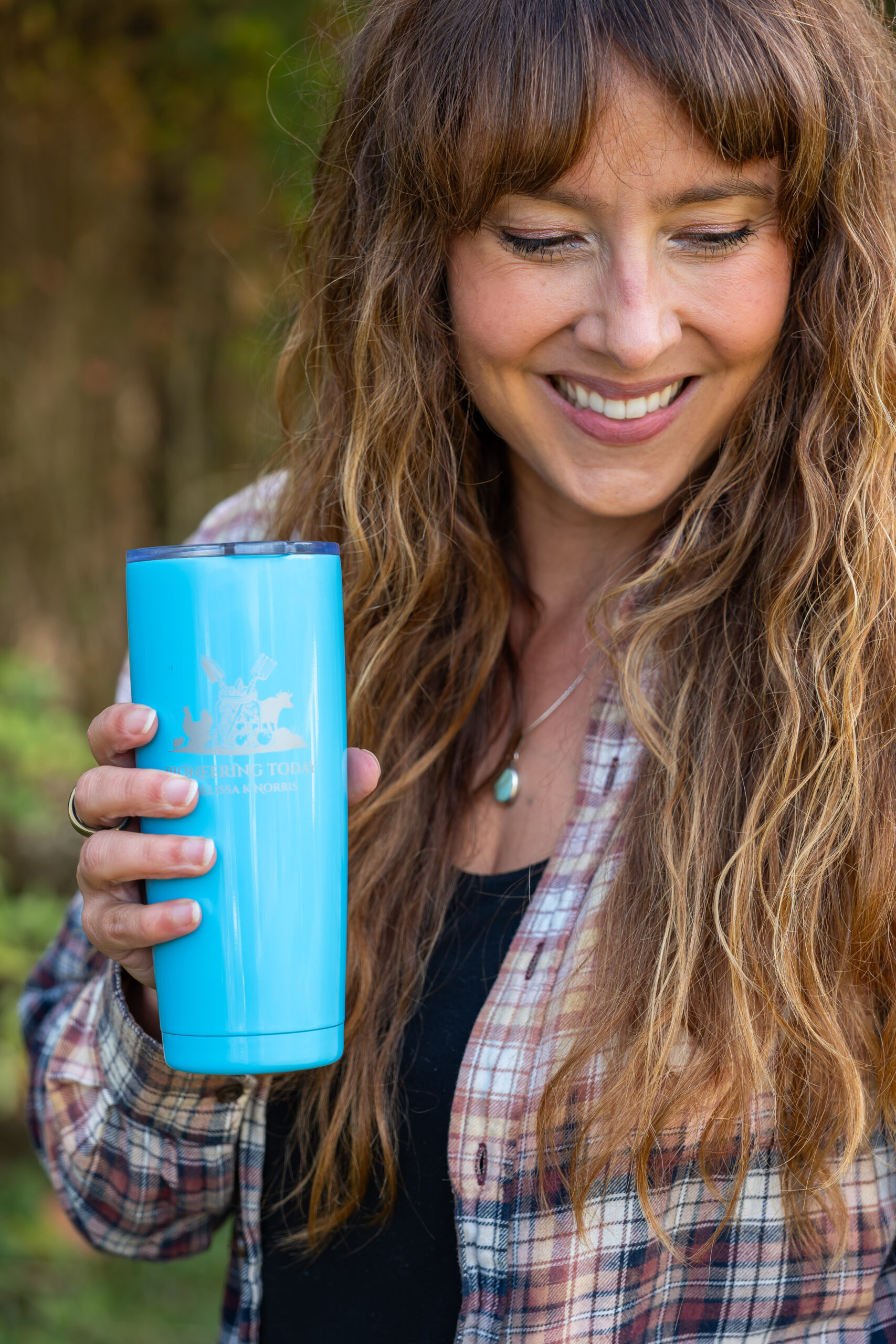 Woman outside holding a stainless steel Pioneering Today tumbler
