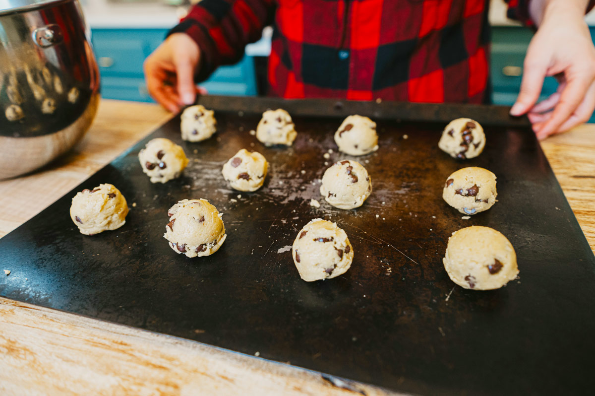 Chocolate chip cookie dough balls on a baking tray.