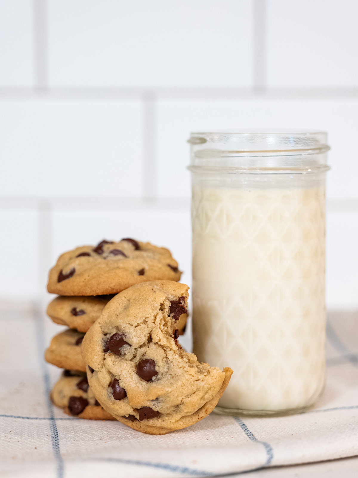 A stack of chocolate chip cookies next to a glass of milk.