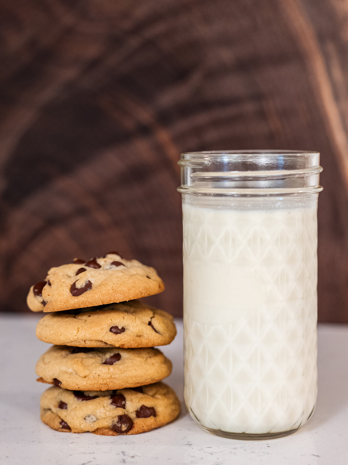 A stack of chocolate chip cookies next to a glass of milk.