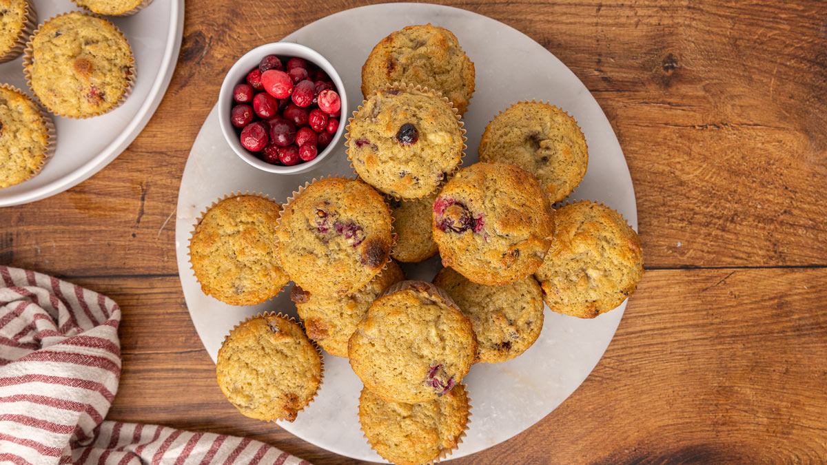 Cranberry muffins stacked on a white plate.