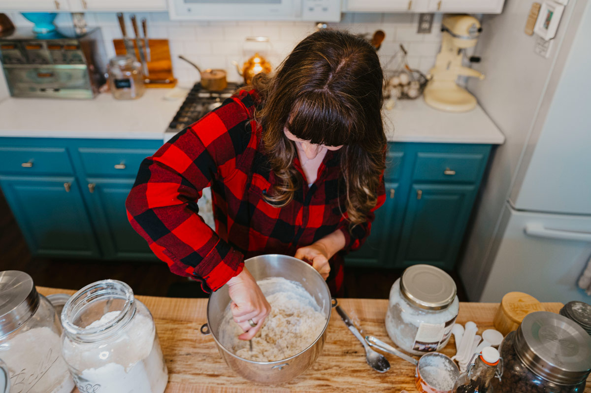 A woman mixing together chocolate chip cookie dough.