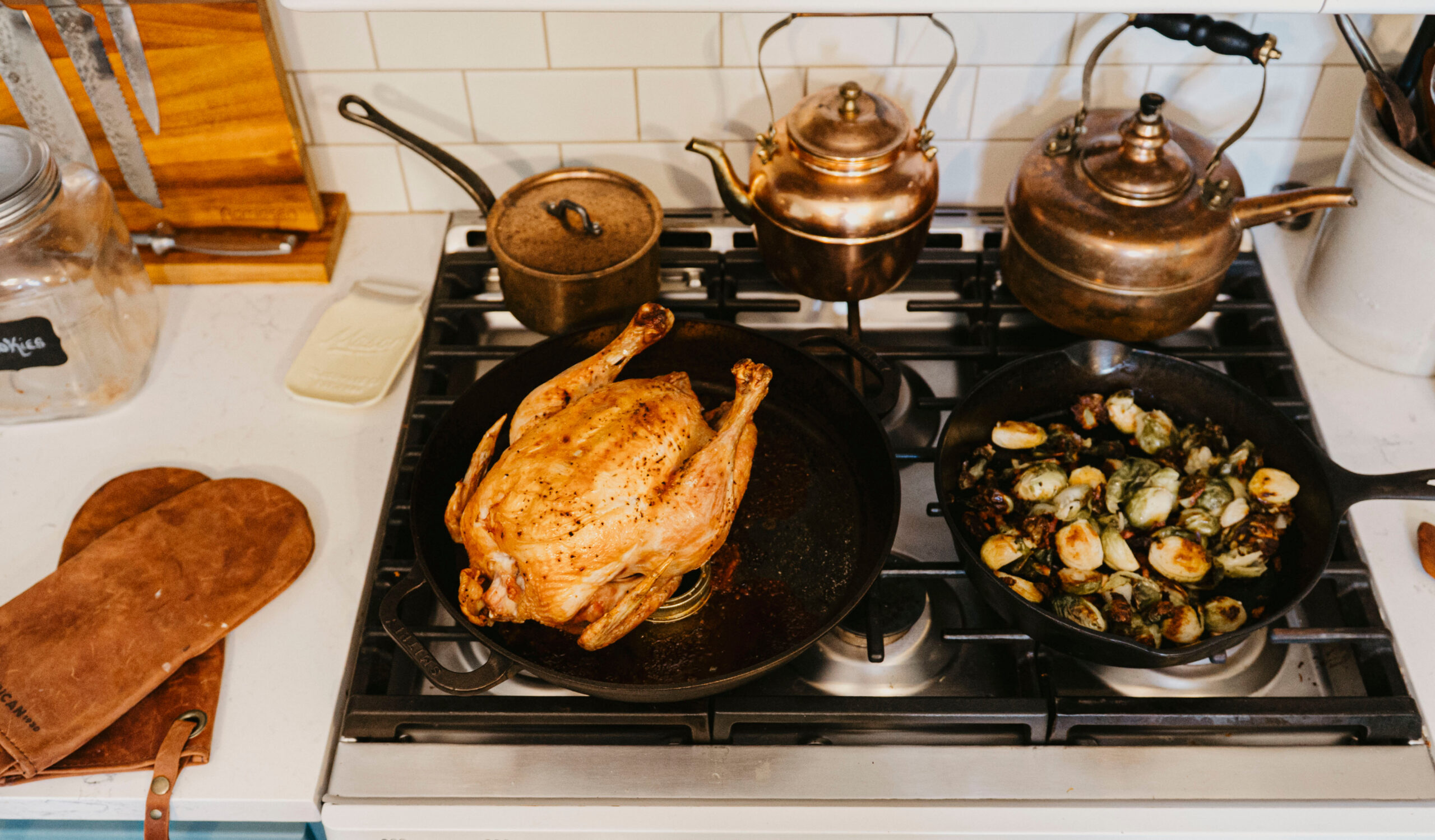 A roasted chicken and sauteed vegetables on a stovetop.