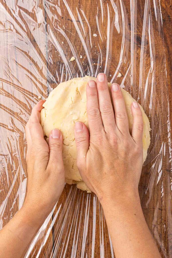 Hands forming pie crust dough into a ball.