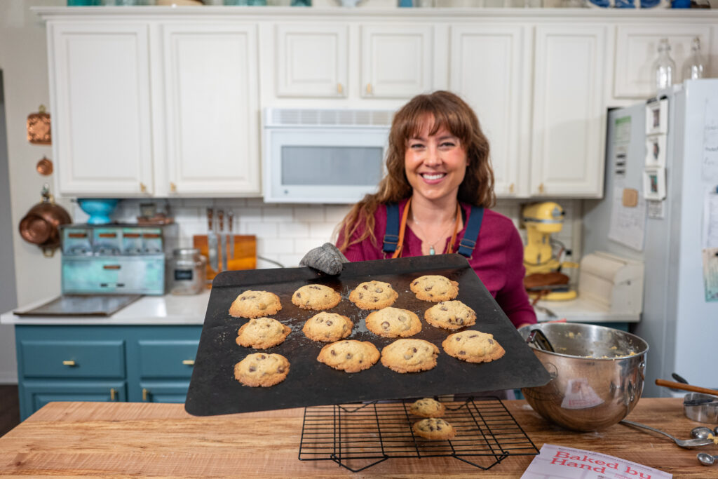 A woman holding a tray of chocolate chip cookies.