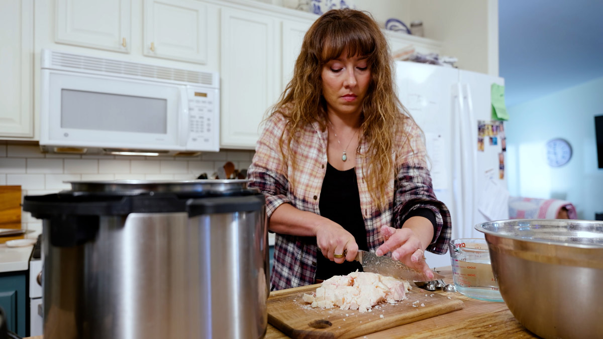 A woman chopping beef fat on a cutting board.