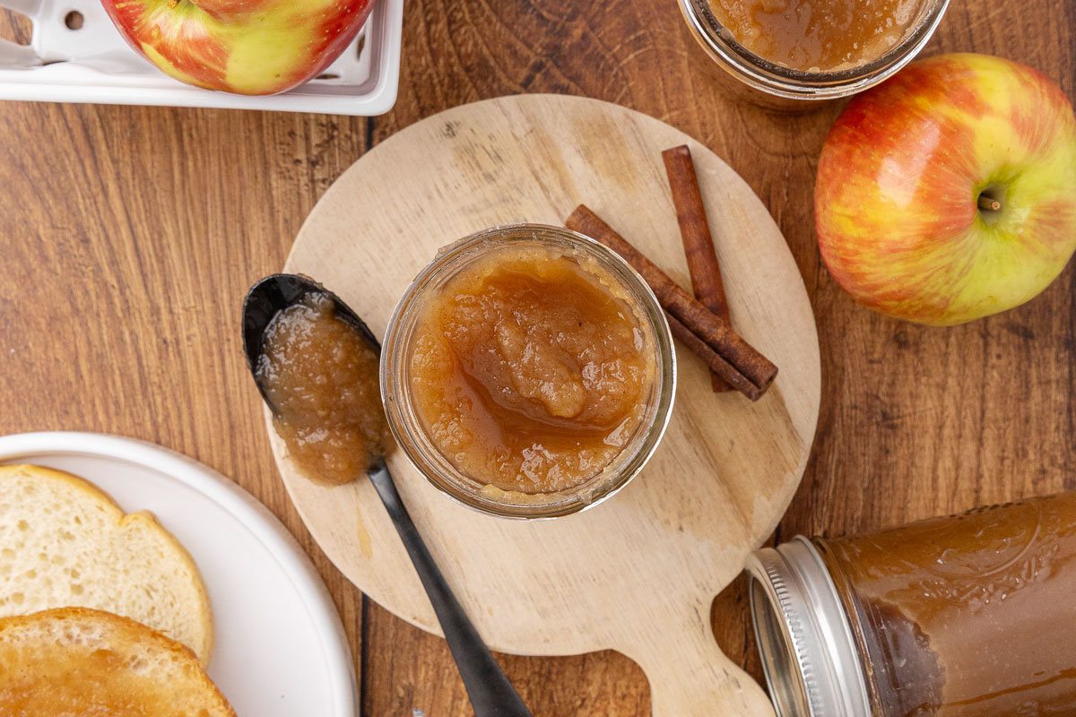 Bird's eye view of an opened jar of apple butter with a spoonful of apple butter sitting next to it to show texture.