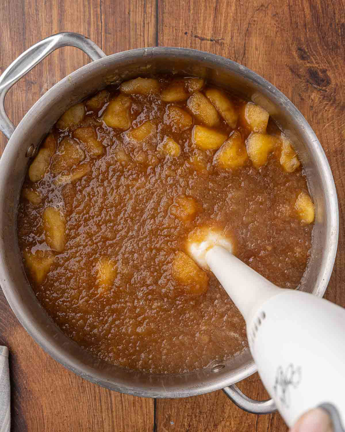 An immersion blender pureeing cooked apple butter.