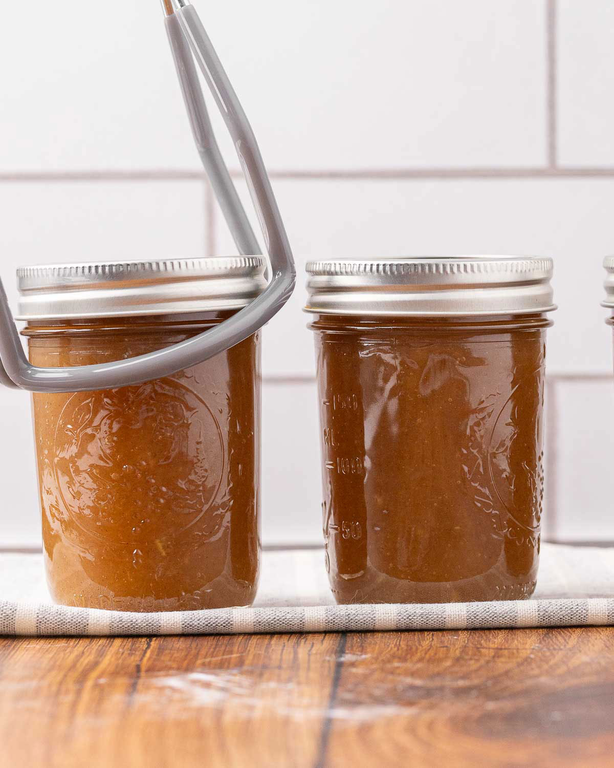 A jar lifter moving a jar of hot apple butter.